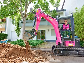 CEO Tim Höttges operates a magenta-colored excavator.