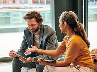 Woman showing man something on a tablet.