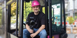 Nick Schneider (Corporate Communications Trainee) sits in the cockpit of a Magenta excavator with his camera equipment.
