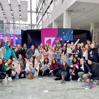 A large group of women looks into the camera, smiling and cheering.
