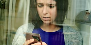 Thoughtful woman looks at a smartphone.
